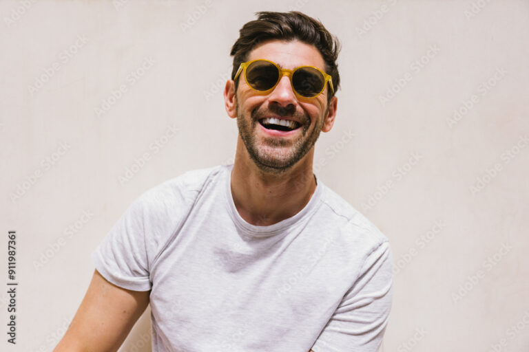 Man wearing sunglasses with a bright smile and casual white t-shirt