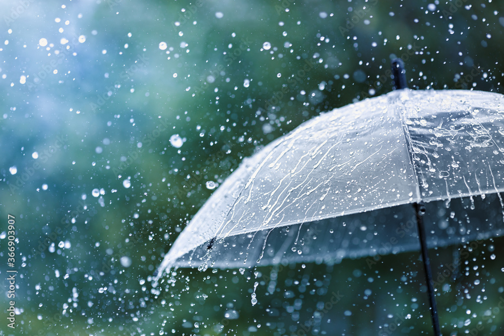 Transparent umbrella under rain against water drops splash background. Rainy weather concept.